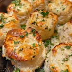 Juicy garlic herb cheese bread bites arranged on a rustic wooden table.
