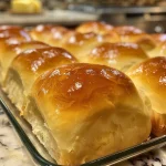 Close-up view of fluffy homemade yeast dinner rolls, golden brown with a light sheen.