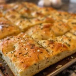 Close-up of a golden-brown Garlic Rosemary Herb Focaccia with a shiny crust.