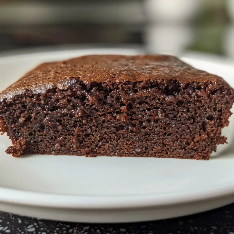 Close-up side view of a slice of moist chocolate cake with glossy icing.