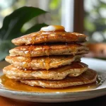 Close-up view of fluffy oat flour pancakes stacked on a plate.