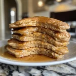 Close-up side view of fluffy protein pancakes topped with a light drizzle of syrup.