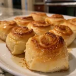 Close-up of golden-brown Greek yogurt rolls on a wooden surface.