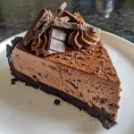 Close-up view of a slice of no-bake chocolate cheesecake with a smooth texture and chocolate topping.