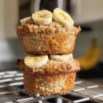 Close-up of golden-brown oat flour banana muffins on a wooden surface.