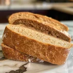 Close-up side view of a loaf of whole wheat sourdough sandwich bread.