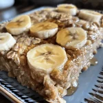 Close-up of Banana Baked Oatmeal topped with slices of banana and a sprinkle of cinnamon.