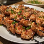 Juicy Bang Bang chicken skewers garnished with green onions and sesame seeds.