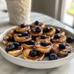 Close-up view of blueberry cottage cheese pancake bites on a plate.