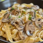 Close-up view of creamy mushroom pasta with fresh parsley on top.