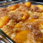 Close-up side view of a delicious peach cobbler dump cake topped with golden brown crust.