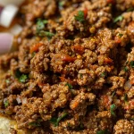 Close-up of juicy taco meat in a skillet, showing rich color and texture.
