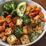A close-up view of a colorful quinoa bowl featuring spiced tofu and roasted vegetables.