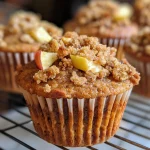 A close-up side view of freshly baked Apple Cinnamon Muffins, showcasing their golden-brown tops and bits of apple.
