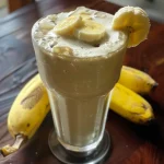 Close-up of a creamy banana milkshake in a glass with crushed ice.
