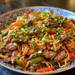 Close-up view of a plate of Beef Chow Mein with colorful vegetables.