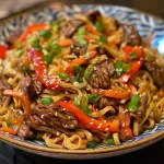A close-up view of stir-fried beef lo mein with colorful vegetables.