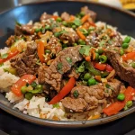 Close-up view of a delicious beef stir-fry with vibrant vegetables and seasoned rice.