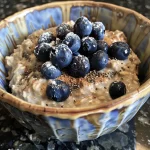Close-up view of a bowl of blueberry overnight oats topped with yogurt and walnuts.
