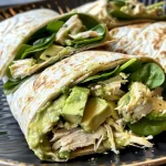A close-up side view of a Chicken Avocado Wrap filled with shredded chicken, diced avocados, and colorful veggies.