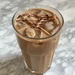Close-up view of a rich Chocolate Cream Cold Brew in a glass, showcasing creamy layers and chocolate drizzle.