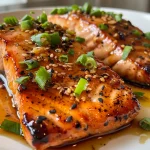 Close-up of crispy honey garlic glazed salmon fillet with garnish.