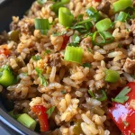 Close-up view of Dirty Rice with Ground Beef showcasing a mix of rice and meat garnished with green onions.