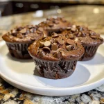 Close-up side view of decadent double chocolate banana muffins with chocolate chips.