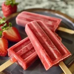 Close-up view of fresh strawberry yogurt popsicles showing juicy strawberries and a smooth yogurt texture.