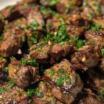 Close-up of juicy garlic butter steak bites garnished with fresh parsley.