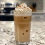 Close-up of a refreshing Iced Vanilla Latte in a glass filled with ice.