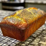 Close-up side view of a lemon poppy seed loaf cake showcasing a moist texture and bright yellow color.