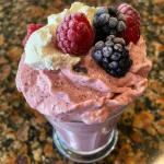 Close-up view of a mixed berry cheesecake smoothie in a clear glass.