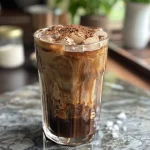 A close-up side view of a glass filled with Mocha Cold Brew Coffee, showcasing its rich brown color.