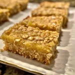 Close-up side view of golden-brown Oatmeal Lemon Creme Bars with a textured topping.