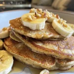 Close-up view of protein pancakes topped with banana slices.