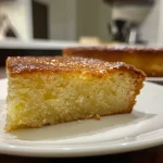 Close-up of a simple dessert featuring a moist, golden-brown cake with a light glaze.