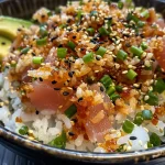 Close-up view of a serving of Spicy Tuna Crispy Rice topped with avocado and sesame seeds.