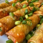 Close-up view of juicy spring rolls with a crispy exterior on a wooden surface.