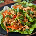 Close view of fresh Thai peanut chicken lettuce wraps made with diced chicken, vegetables, and toppings.
