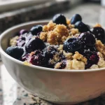 Close-up view of a baked blueberry oatmeal bowl with cottage cheese and fresh blueberries.