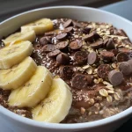 Close-up view of a bowl of Chocolate Banana Oatmeal topped with banana slices.