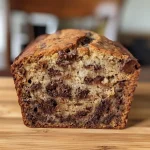 Close-up view of moist chocolate chip banana bread with a golden crust and chocolate chips.