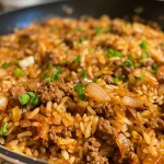 Close-up of a hearty beef onion rice skillet with golden caramelized onions and steaming rice.