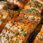 Close-up view of golden-brown garlic butter salmon bites garnished with fresh parsley.