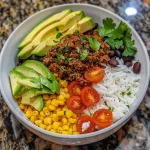A close view of a Ground Beef Taco Rice Bowl with colorful ingredients.