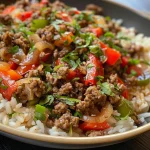 Close-up of a bowl filled with beef and pepper stir-fry over rice.
