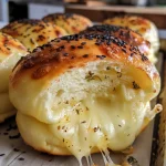Close-up of a golden brown stuffed cheese bun, revealing melted cheese inside.