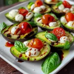 Close-up view of a halved avocado filled with cherry tomatoes and mozzarella.