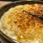 Close-up view of creamy vanilla rice pudding brûlée with a golden, crackly sugar top.
